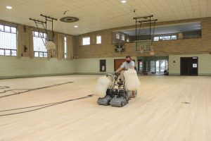 Team professionally restoring existing sports flooring in a school gym