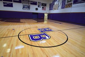 School gym featuring logo on safe, high-quality sports flooring restored for student use