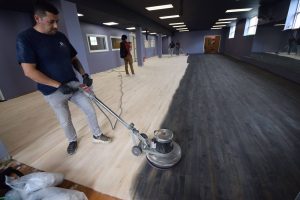 Milburn Flooring team sanding hardwood gym floors as part of professional refinishing services for schools and athletic facilities