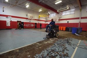 Removing damaged athletic flooring panels from school gym